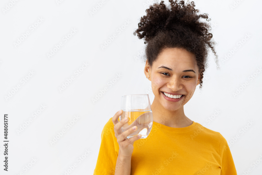 Healthy lifestyle concept. Smiling young African American woman holding glass of fresh clean water looking at camera and smiling friendly, White background, copy space Healthy lifestyle concept. Smiling young African American woman holding glass of fresh clean water looking at camera and smiling friendly, White background, copy space