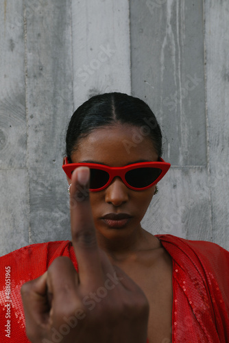 Rebellious black and young woman showing middle finger on the street. Vertical. © face_reader_img