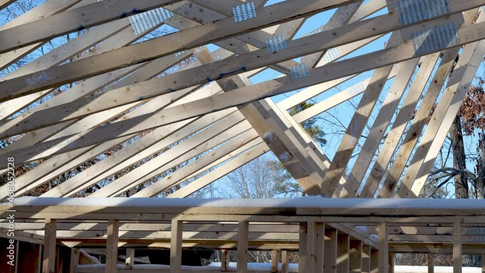Wooden roof truss being installed on a new home construction project with blue sky in the background. Hand held clip. Wooden roof truss being installed on a new home construction project with blue sky in the background. Hand held clip.