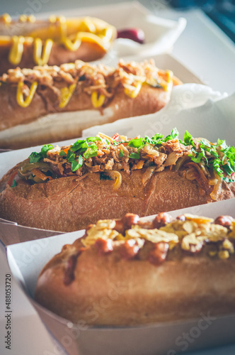 Freshly prepared assorted hotdogs in a paper box. Food delivery or take away food concept.