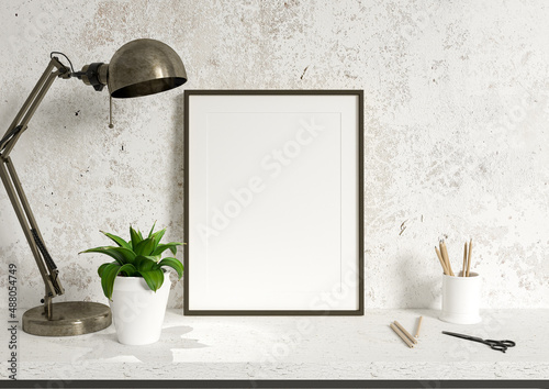 Single 8x10 Vertical Black Frame mockup on white desk and a stone wall with green plant, lamp and scissors. Loft style frame mockup on a desk. 3D Rendering