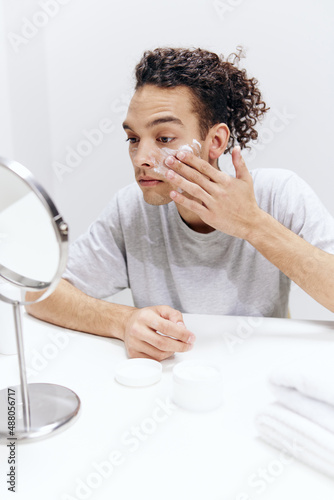 handsome guy sit in front of the mirror  facial skin care skin health