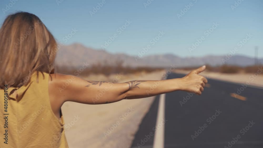 Back view of hipster girl wanderlust walking on asphalt road in wild lands on southwest getting to National park by foot, female tourist with rucksack having journey in Arizona hitchhiking on the way Back view of hipster girl wanderlust walking on asphalt road in wild lands on southwest getting to National park by foot, female tourist with rucksack having journey in Arizona hitchhiking on the way