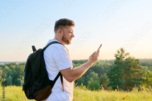 Middle aged bearded man with smartphone backpack on hike, making video call