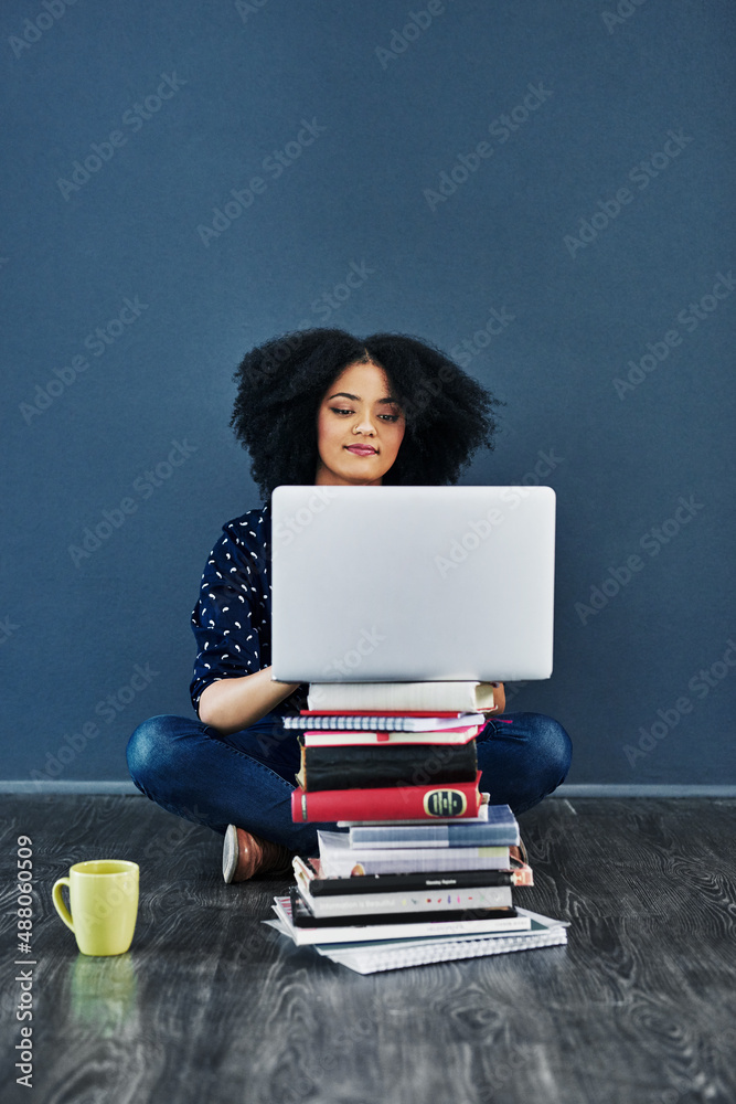 Always seek out knowledge. Studio shot of a young woman using a laptop with books stacked in front of her against a blue background. Always seek out knowledge. Studio shot of a young woman using a laptop with books stacked in front of her against a blue background.