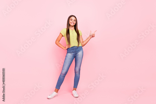 Photo of positive promoter lady direct finger empty space wear green top jeans sneakers isolated pink color background © deagreez