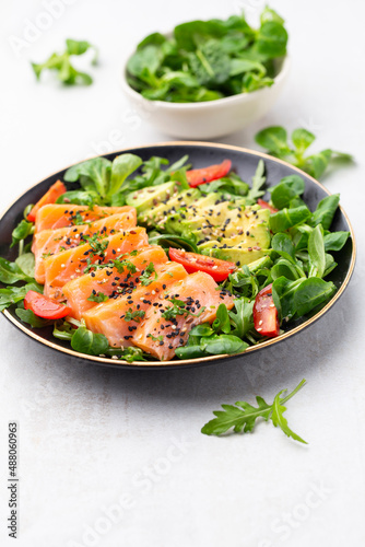 Salmon fish fillet with fresh salad  avocado top view.