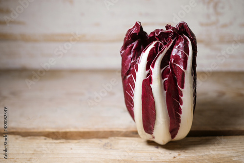 Radicchio Treviso or Italian chicory, red leaf vegetable standing on a rustic wooden table, copy space, selected focus photo