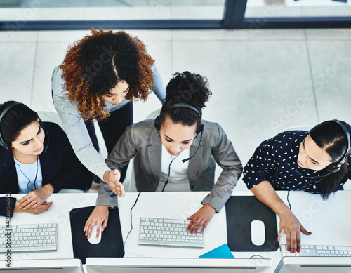 Commitment always shows from every employee on our side. High angle shot of a group of women working in a call centre. photo