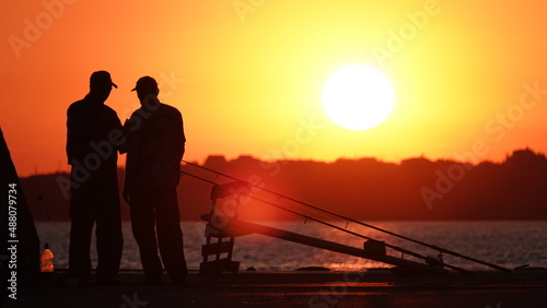 Silhouette of fishermen on the pier at sunset