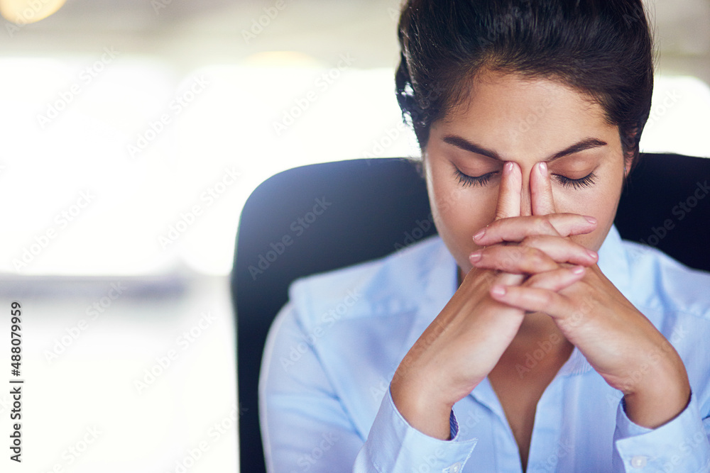Her job can get quite hectic at times. Shot of a young businesswoman looking stressed while sitting in her office chair. Her job can get quite hectic at times. Shot of a young businesswoman looking stressed while sitting in her office chair.