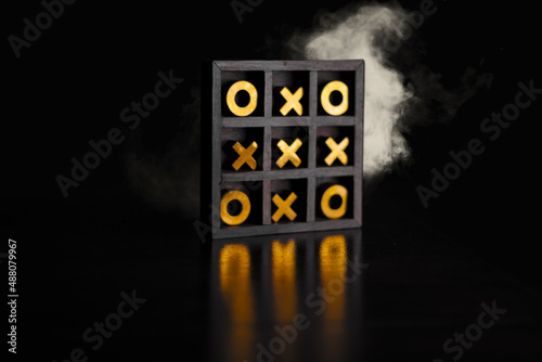 Golden tic-tac-toe wooden board in the smoke.