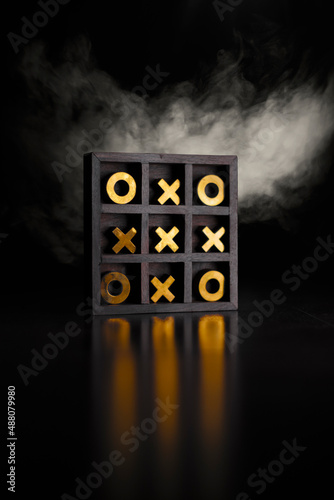 Golden tic-tac-toe wooden board in the smoke.