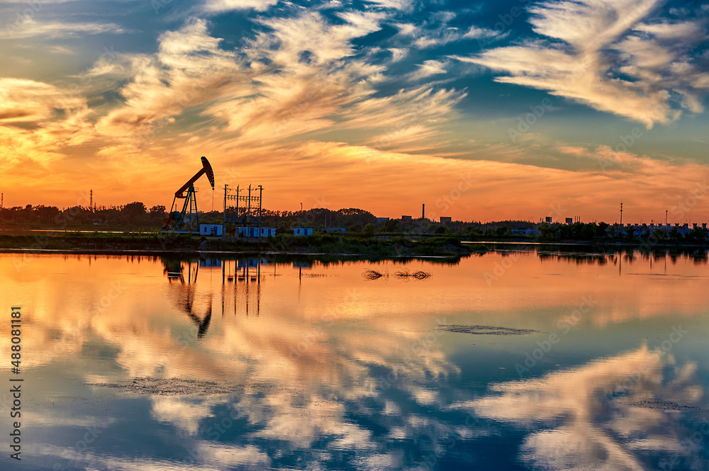 The  oil sucking machines at lakeside sunrise in Daqing oil fields, China.