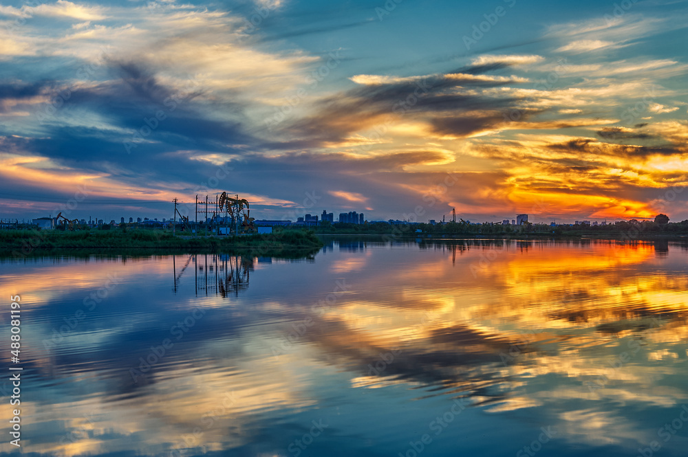 The  oil sucking machines at lakeside sunrise in Daqing oil fields, China.