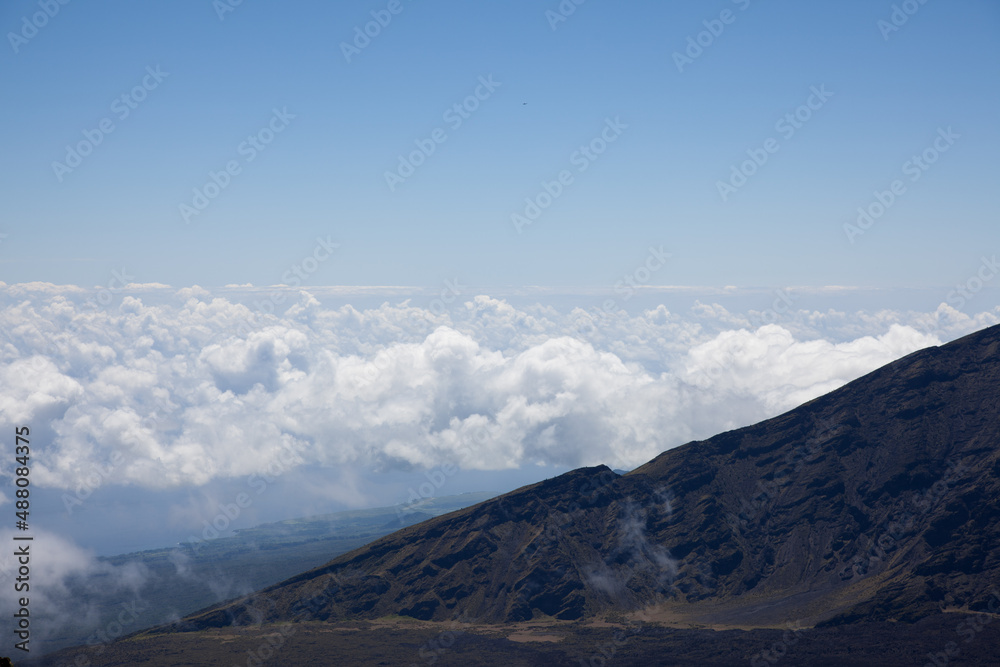 A scenic view above a blanket of white fluffy clouds seen from the top of Mt. Haleakala in Maui, Hawaii. 
