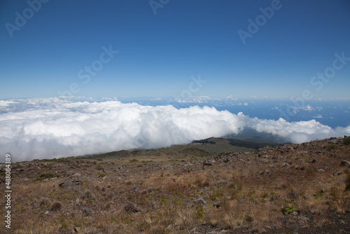 A scenic view above a blanket of white fluffy clouds seen from the top of Mt. Haleakala in Maui, Hawaii. 