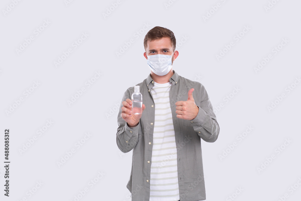 Man Holding Hands Antiseptic Wearing Medical Mask Showing Thumb Up Isolated. Hands sanitizer Man Holding Hands Antiseptic Wearing Medical Mask Showing Thumb Up Isolated. Hands sanitizer