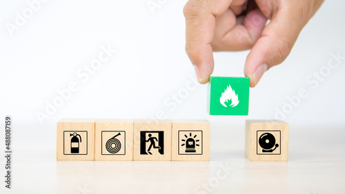 Hand choose cube wooden block stack with fire icon and door exit sing or fire escape with prevent icon and fire extinguisher and emergency protection symbol for safety and rescue.