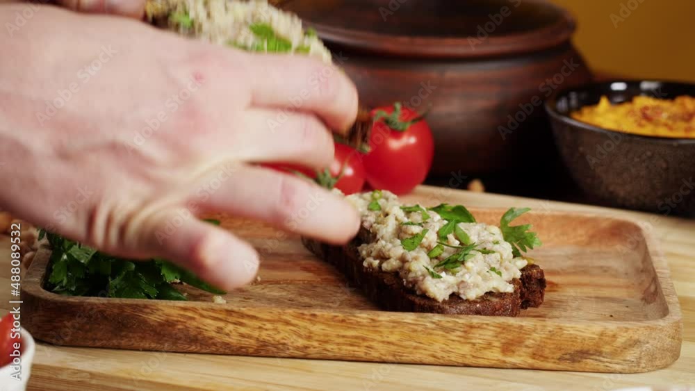 Israeli cuisine. Hands taking forshmak with black rye bread decorated