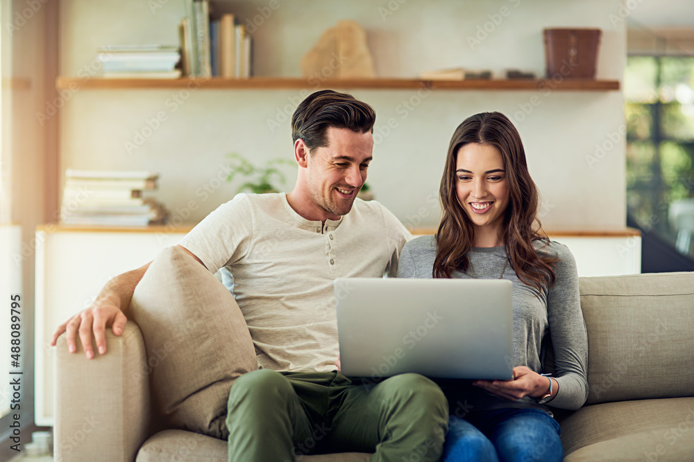 The online experience is even better when its shared. Shot of a happy young couple using a laptop together on the sofa at home. The online experience is even better when its shared. Shot of a happy young couple using a laptop together on the sofa at home.