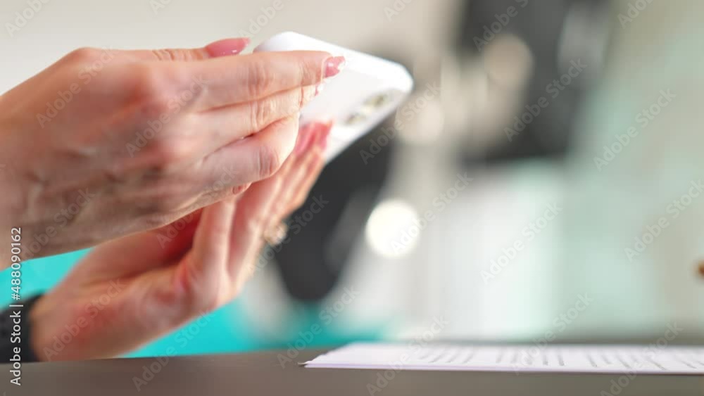 Browsing a new white up-to-date mobile phone. Female hands turn the mobile to see wider angle. Close up. Blurred backdrop. Browsing a new white up-to-date mobile phone. Female hands turn the mobile to see wider angle. Close up. Blurred backdrop.