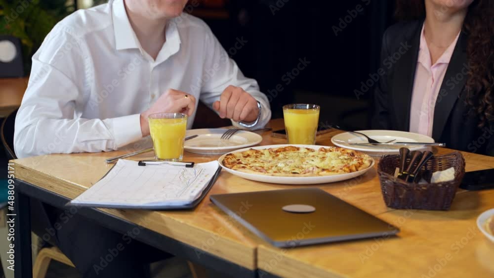 Office colleagues came to have business lunch at café. People wearing official clothes sit at the table with pizza and juice. Office colleagues came to have business lunch at café. People wearing official clothes sit at the table with pizza and juice.