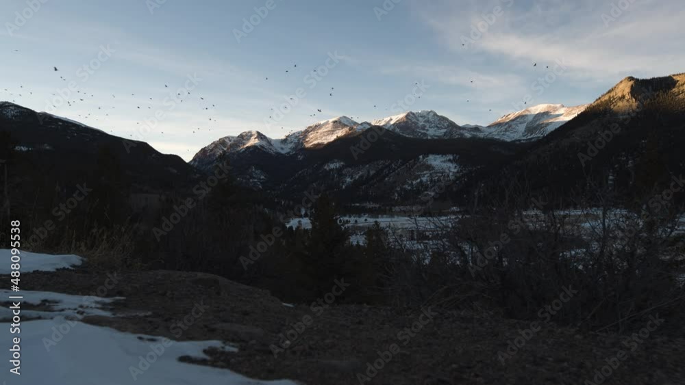 Birds flying in front of distant mountains as the sun is cresting the peaks in sunset Birds flying in front of distant mountains as the sun is cresting the peaks in sunset