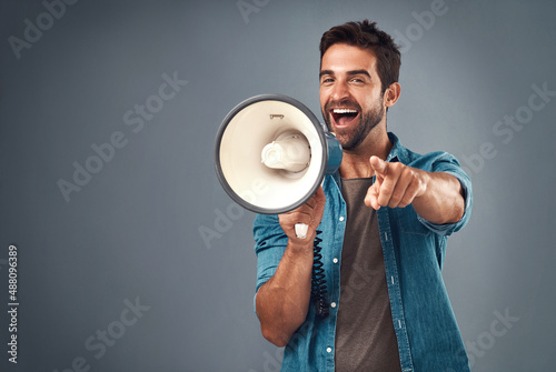 Youre our winner of the day. Studio shot of a handsome young man using a megaphone against a grey background. photo