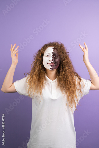Pleasant looking cheerful curly redhead fan football woman with face painted in Qatar flag posing with raised hands on violet background.