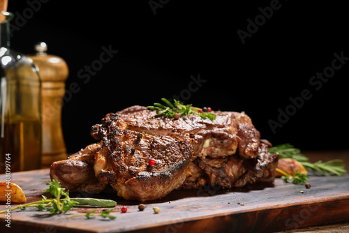 Cooked juicy steak meat beef with seasoning on wooden chopping board.