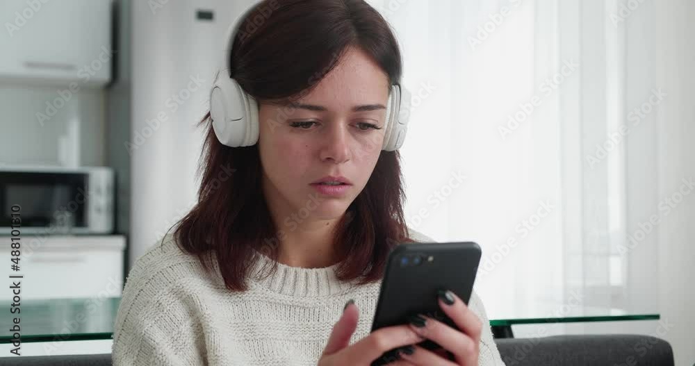 Sad woman with headphone reading bad news on smartphone Sad woman with headphone reading bad news on smartphone