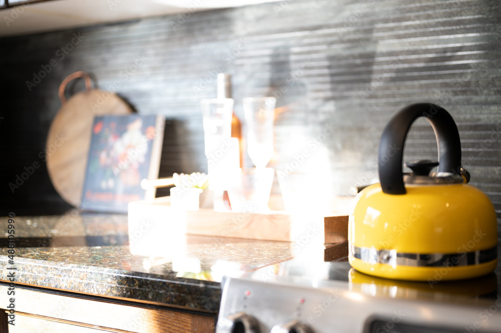 yellow kettle pot on the stove with rock tiles in background and wine glasses yellow kettle pot on the stove with rock tiles in background and wine glasses