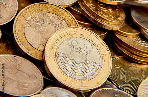 monedas de mil pesos colombianos sobre un montón de otras monedas de mas bajo valor comercial  photo