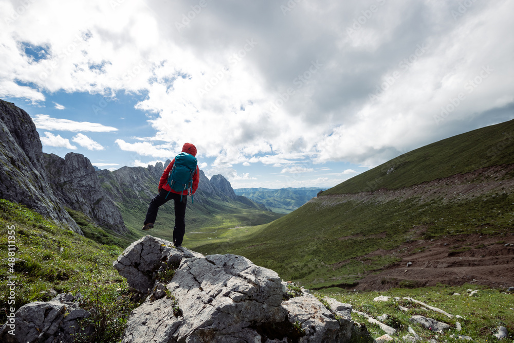 Woman backpacker hiking on alpine mountain peak