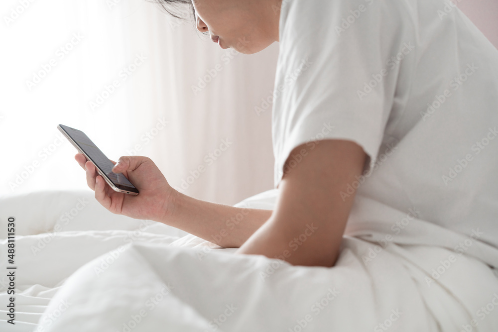 sleepy young man using smartphone on the bed 