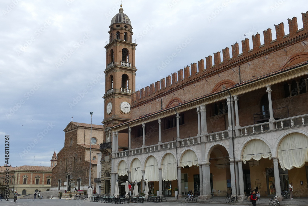 piazza del popolo in Faenza surrounded by palaces with arcades and the cathedral and the tower in the background
