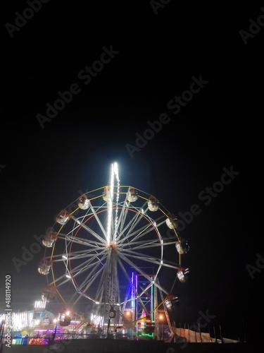 A giant wheel of fair in India,the Largest Ferris Wheel in the World, silhouette giant swing on twilight time of the day - can use to montage or portcard. Visible noise, india