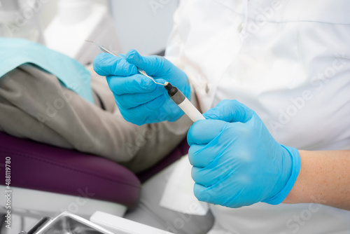 Composite filling material used in dentistry. Dentist's hands in sterile gloves close-up.
