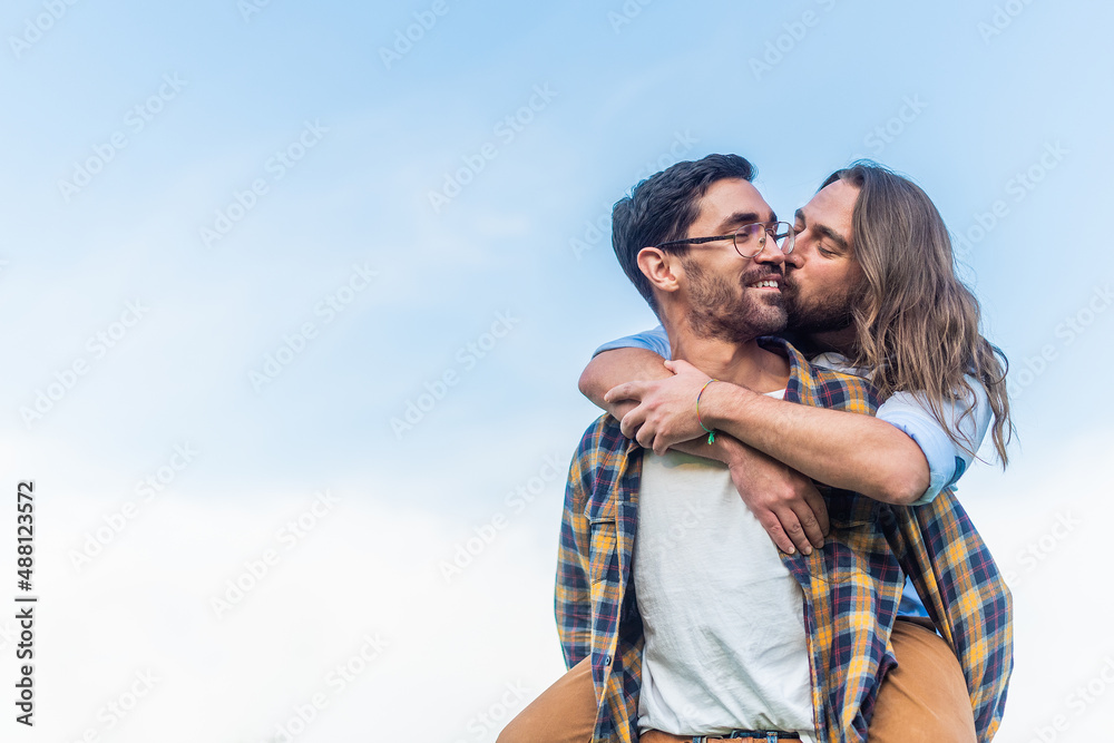 man carrying his partner on back while kissing on cheek man carrying his partner on back while kissing on cheek