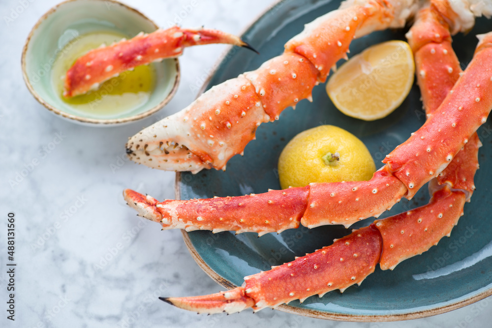 Closeup of boiled legs and claws of kamchatka crab served on a turquoise plate, horizontal shot on a light-grey marble surface Closeup of boiled legs and claws of kamchatka crab served on a turquoise plate, horizontal shot on a light-grey marble surface