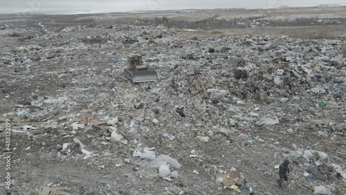 bulldozer tractor pushes garbage from a mountain in a city dump