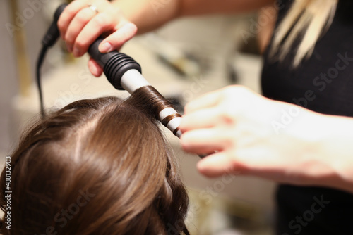 Hairdressers hands doing hair with a curling iron
