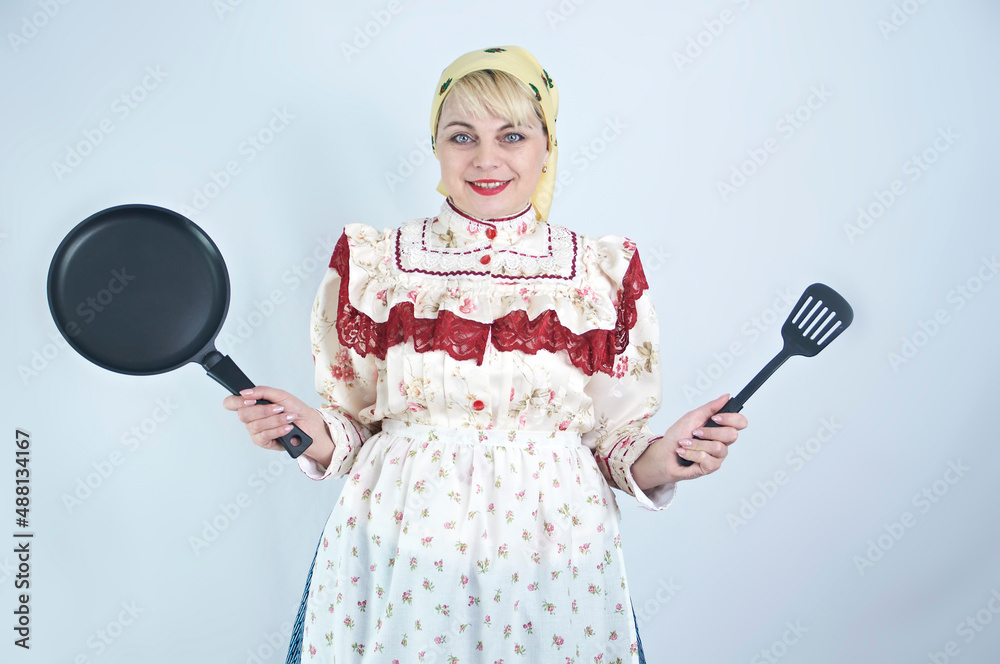 Pretty woman in Hungarian national folk clothes dress holds pan and cooking vane on white background Pretty woman in Hungarian national folk clothes dress holds pan and cooking vane on white background