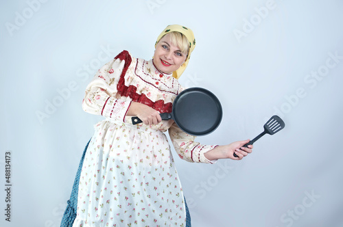 Pretty woman in Hungarian national folk clothes dress holds pan and cooking vane on white background