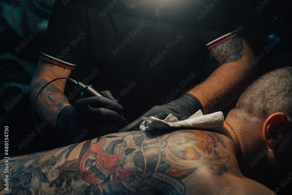 Tattoo artist holding a machine while working in a studio Stock Photo | Adobe Stock Tattoo artist holding a machine while working in a studio Stock Photo | Adobe Stock
