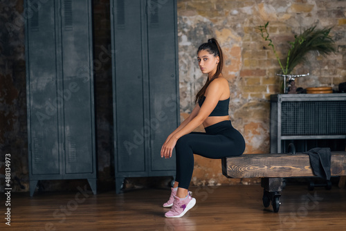 Sporty woman in sportswear resting on bench at fitness.