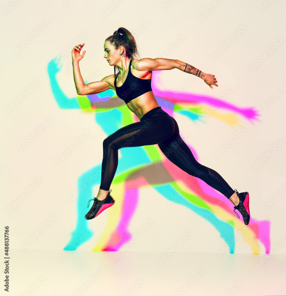 Sporty woman runner in silhouette. Photo of muscular woman in black sportswear on white background with effect of rgb colors shadows. Dynamic movement. Side view. Sport and healthy lifestyle