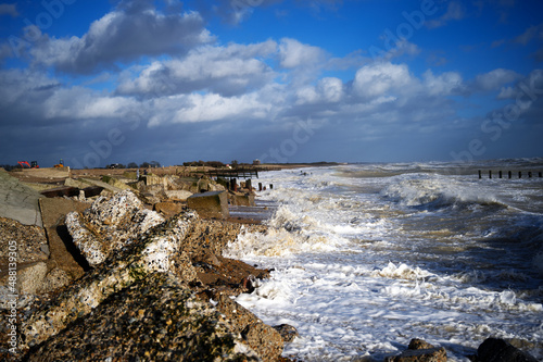 Climping Beach in West Sussex, Southern England on the English Channel with waves braking on the rocks after Storm Eunice with old sea defences already damages holding the sea back. photo