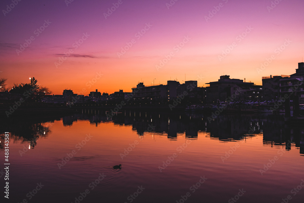 日没後の街のシルエットと運河に反射する街